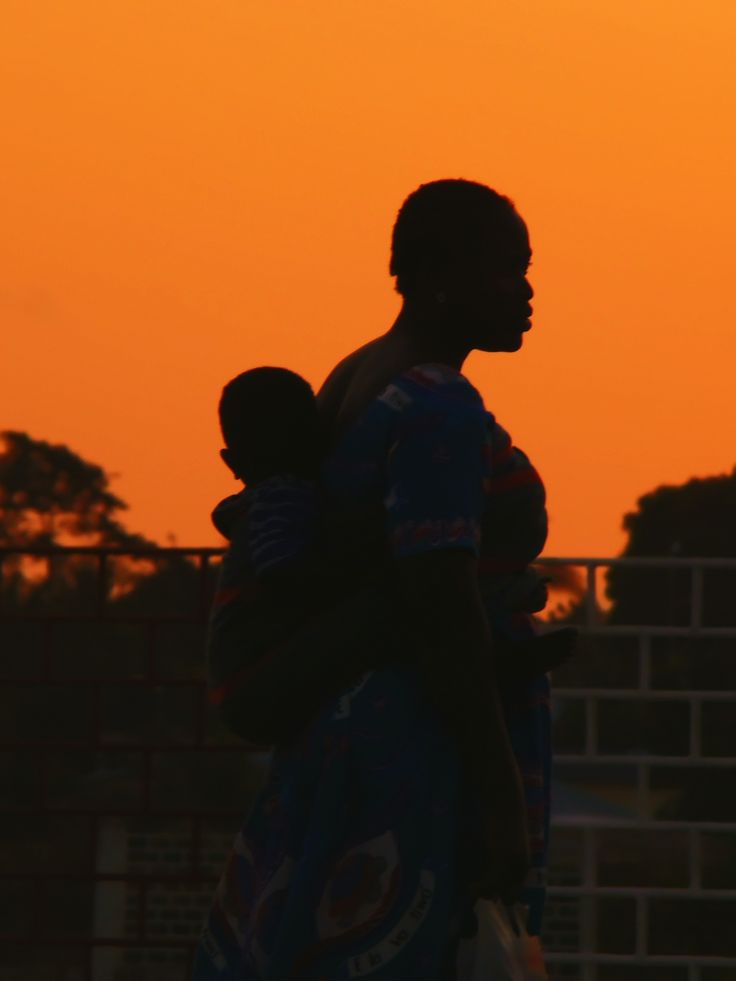A mother holding her child at sunset